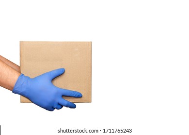 Hand In Blue Medical Glove Gives Cardboard Box.?oncept Of Safety Mail Goods Courier Delivery In Virus Or Coronavirus Quarantine. Donation Concept. Voluntary Assistance To Those In Need.Volunteering