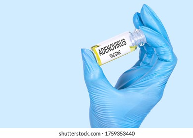 A Hand In A Blue Medical Glove Holds A Bottle With The Inscription ADENOVIRUS VACCINE.