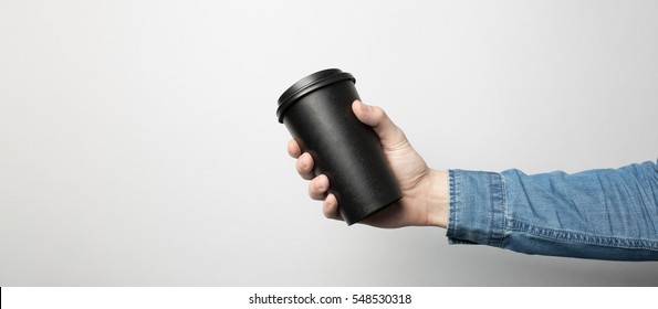 Hand In Blue Shirt Is Holding A Black Paper Cup