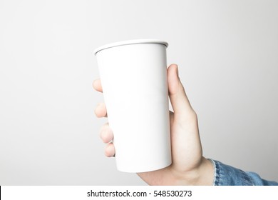 Hand In Blue Shirt Is Holding A White Paper Cup