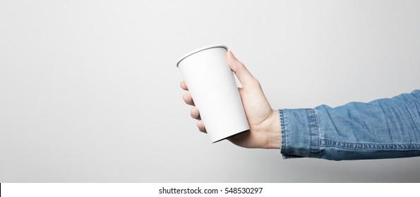 Hand In Blue Shirt Is Holding A White Paper Cup