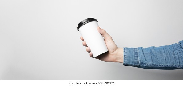 Hand In Blue Shirt Is Holding A White Paper Cup