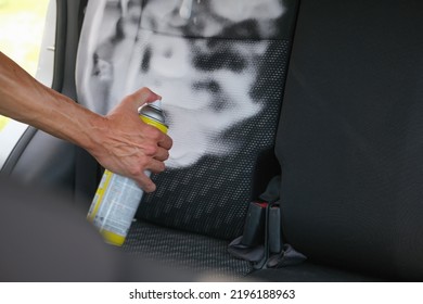 hand with a bottle of cleaning agent sprays foam on the seats of the passenger compartment of a car, takes care of salon of the auto