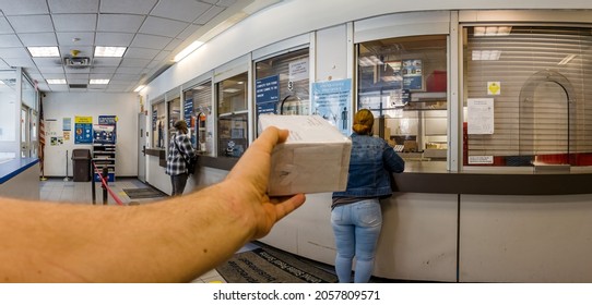Hand with a box package, Very wide-angle, Fisheye, Almost empty only a few customers in USPS post office in New York, the Bronx, 2100 White Plains Rd, 10462, United States of America, 10.13.2021