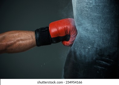 Рука боксера и пробивая мешок на черном фоне