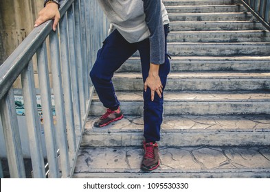 Hand Of The Boy Holding The Knee Because Of Injury Pain In Leg, Can Not Walk Up The Stairs.