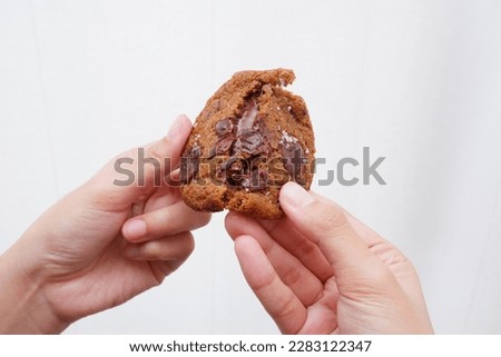 Hand breaking a chocolate chip cookie