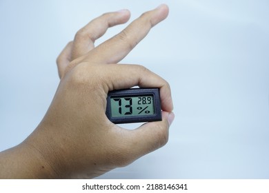 The Hand Of A Brown-skinned Man Carrying A Room Humidity Meter (hygrometer)