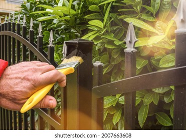 hand with brush painting iron fence