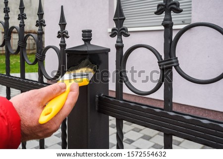 hand with brush painting iron fence 