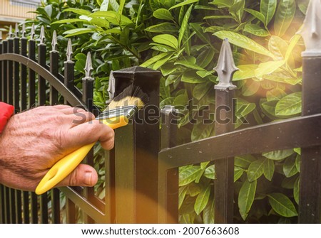 hand with brush painting iron fence