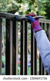 Hand With Brush Painting Metal Fence.