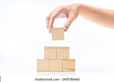 Hand build a pyramid from a wooden block isolated over white background