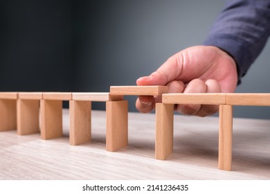 Hand build a toy bridge by wooden blocks and going to add the final piece between the gap to complete, concept of help solution, solve the disconnect problem