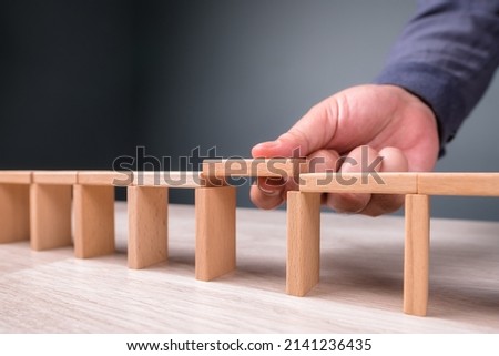 Hand build a toy bridge by wooden blocks and going to add the final piece between the gap to complete, concept of help solution, solve the disconnect problem