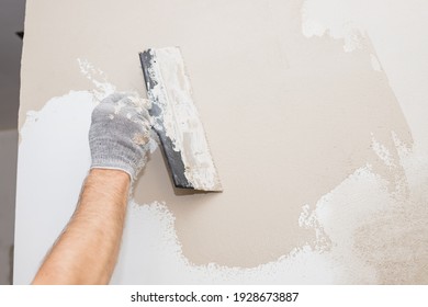 hand of builder worker plastering at wall.Renovation workers hand plastering the wall.Construction finishing works.work aligns with a spatula wall.process of applying layer of putty trowel - Shutterstock ID 1928673887