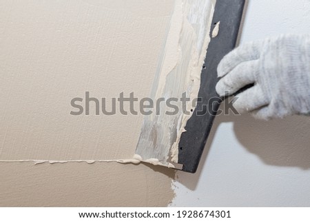hand of builder worker plastering at wall.Renovation workers hand plastering the wall.Construction finishing works.work aligns with a spatula wall.process of applying layer of putty trowel