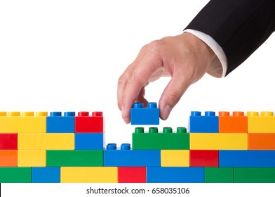 hand building up a wall by stacking up block