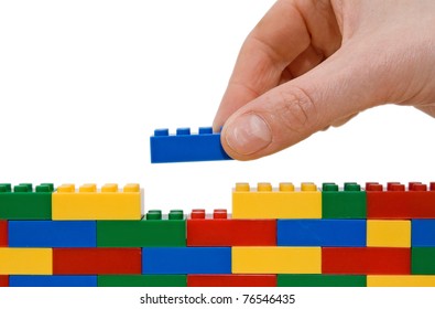 	hand building up a wall by stacking up lego.