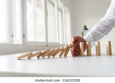 Hand Of A Business Advisor Stooping Domino Effect By Intervening At The Right Moment.