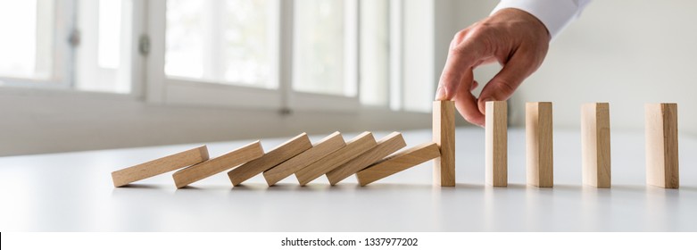 Hand Of A Business Crisis Manager Stopping Falling Dominos To Prevent A Total Collapse And Establish Stability.