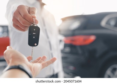 Hand Of Business Man Gives The Car Key, Close-up Image A Man Buys A Car And Receives Keys From The Seller.