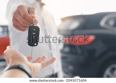 Hand of business man gives the car key, Close-up image a man buys a car and receives keys from the seller.