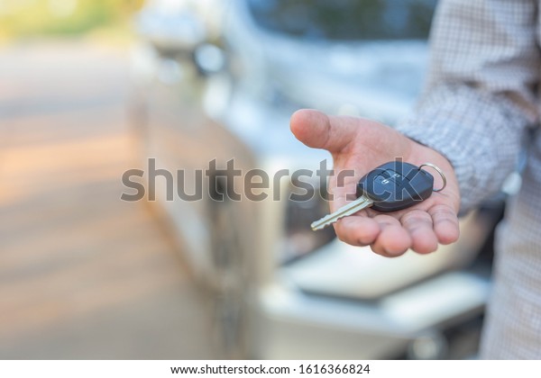 Hand of business man gives the car key -\
transportation and ownership\
concept