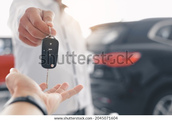 Hand of business man\
gives the car key, Close-up image a man buys a car and receives\
keys from the seller.