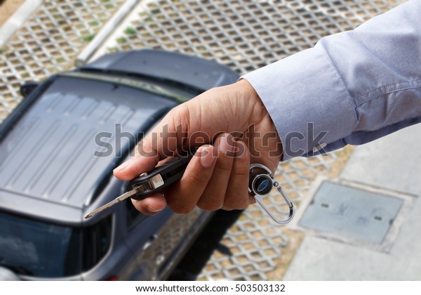 Hand of business man gives the car key with top\
view car outdoor