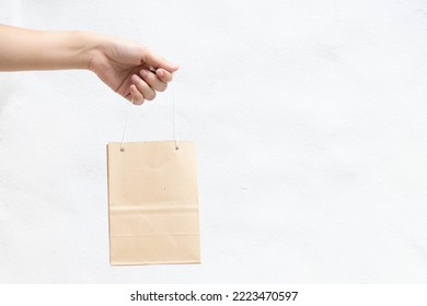 Hand Of Business Woman Hold Brown Paper Shopping Bag On White Concrete Background