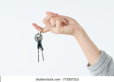 Hand of business woman or real estate agent with keys from new flat or house hanging on the finger. She welcomes to buy a flat or house. Isolated on white background