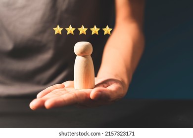 Hand of a businessman chooses a smiley face on wooden peope. 5 Star Satisfaction.