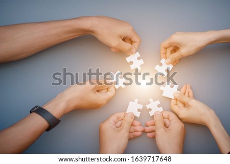 The hand of a businessman holding a paper jigsaw And solve the puzzle together. The business team assembled a jigsaw puzzle. A business group wishing to bring together the puzzle pieces 商業照片 © 