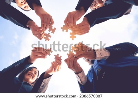 The hand of a businessman holding a paper And solve the puzzle together. The business team assembled a puzzle. A business group wishing to bring together the puzzle pieces