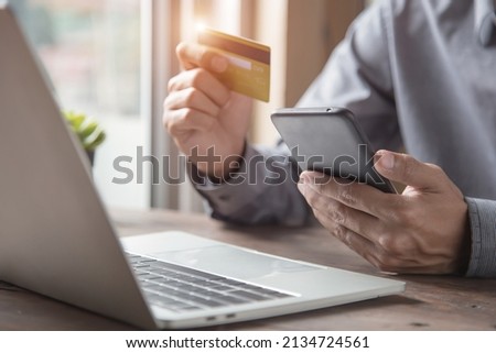 Hand businessman holding smartphone and use credit card to spend money or pay online shopping and services.