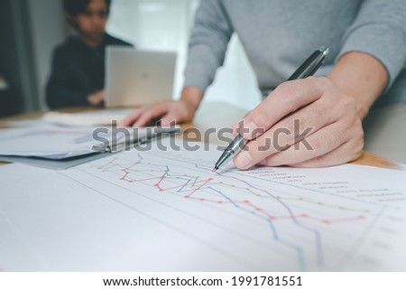 Hand of businessman point to graph. is discussing together in conference room talk about Report, Sales, Target, Marketing, Concept.
