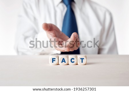 Hand of a businessman presenting the wooden cubes with the word fact. Facts, truth or accurate information in media news or business concept.

