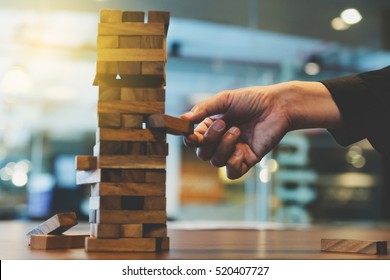 Hand des Geschäftsmanns, der in einem modernen Büro Holzblock auf den Turm zieht oder platziert. Plan und Strategie im Geschäftsleben. unscharfer Hintergrund