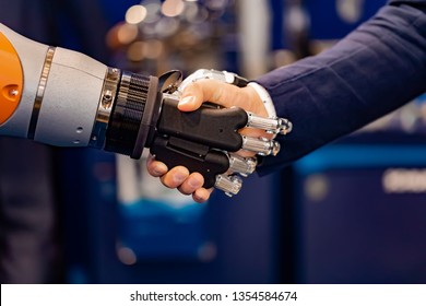 Hand Of A Businessman Shaking Hands With A Robot. The Concept Of Human Interaction With Artificial Intelligence.