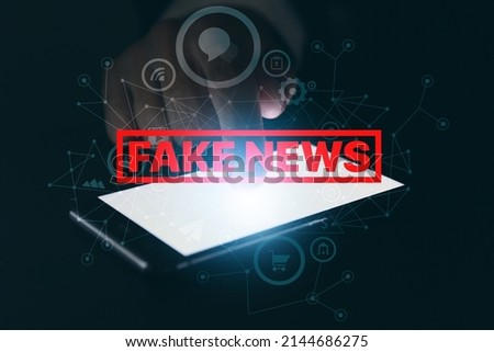 Hand of businessman with smartphone and text FAKE NEWS on dark background