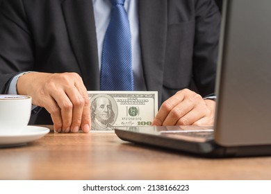 Hand Of A Businessman In A Suit Holding US Dollars Banknote While Sitting In The Office. Close-up Photo. Business And Finance Concept