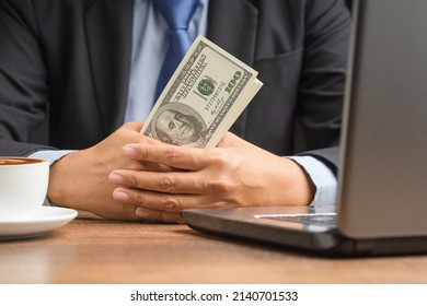 Hand Of A Businessman In A Suit Holding US Dollars Banknote While Sitting In The Office. Close-up Photo. Business And Finance Concept