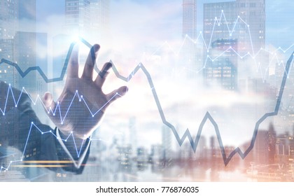 Hand of a businessman wearing a suit interacting with a graphs, a foggy city background. Double exposure toned image mock up