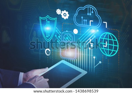 Hand of businessman working with tablet computer over blue background with glowing immersive cyber security interface. Concept of data protection. Toned image
