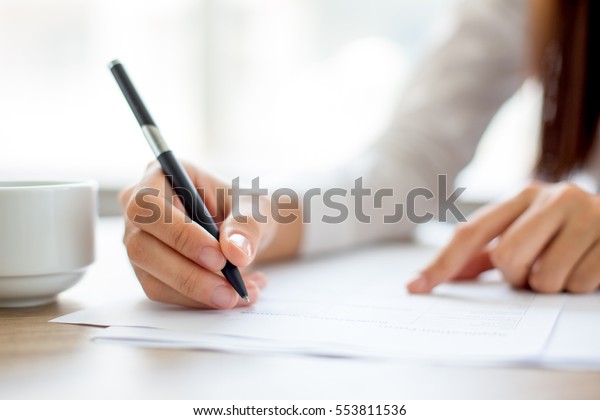 Hand of\
businesswoman writing on paper in\
office