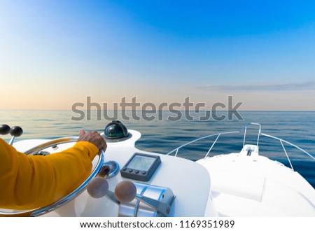 Hand of captain on steering wheel of motor boat in the blue ocean during the fishery day. Success fishing concept. Ocean yacht