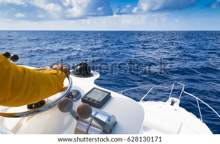 Hand of captain on steering wheel of motor boat in the blue ocean
