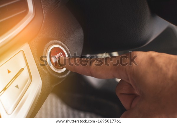 Hand of car driver press to the\
engine start/stop button for engine ignition in a luxury\
car.