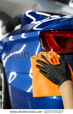 Hand car drying with microfiber in detailing auto service. Cleaner worker dry body car after washing automobile
